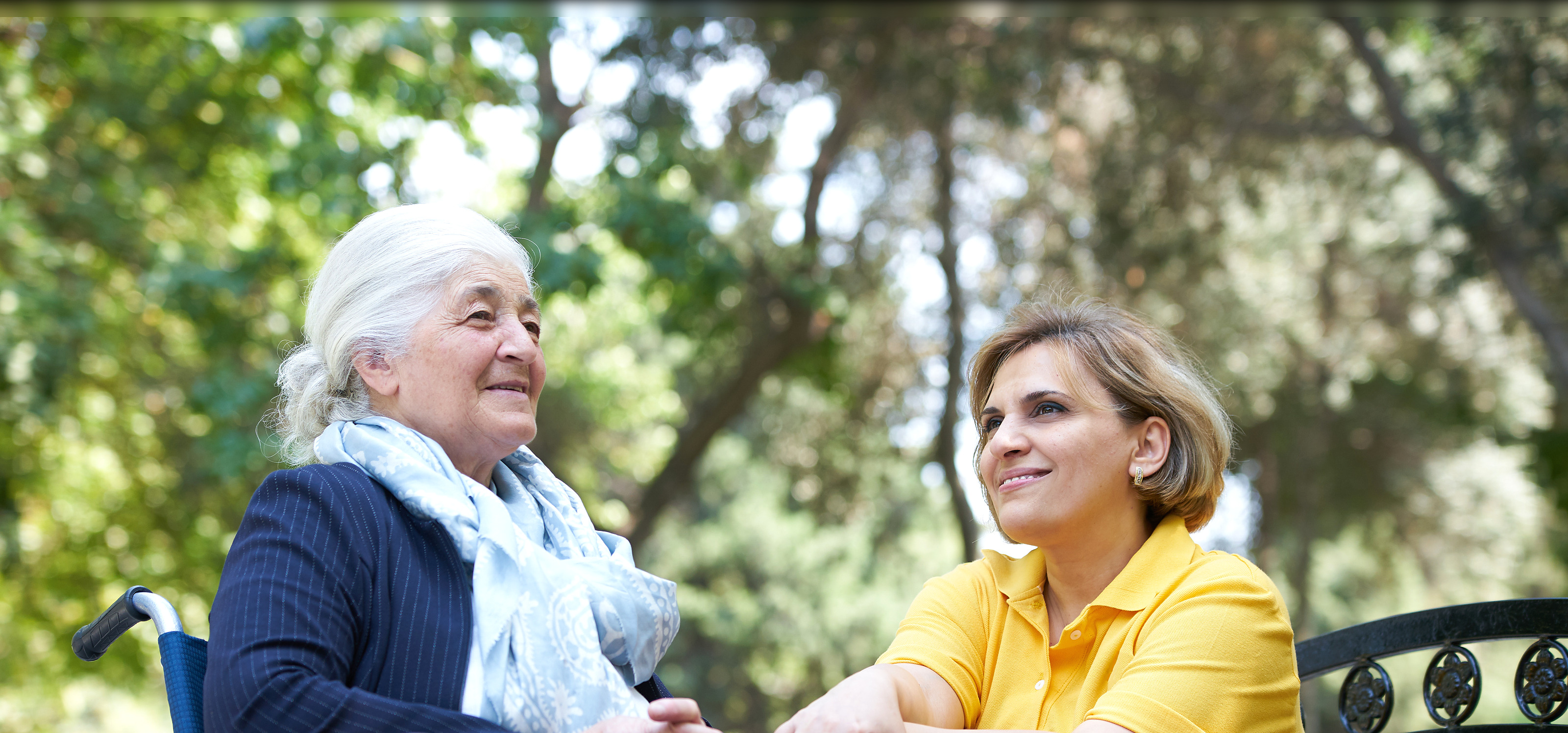 A resident and a caregiver laughing together outdoors